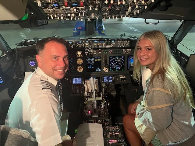 Michael Gonzales in his pilot uniform with his daughter Emma in an airliner cockpit