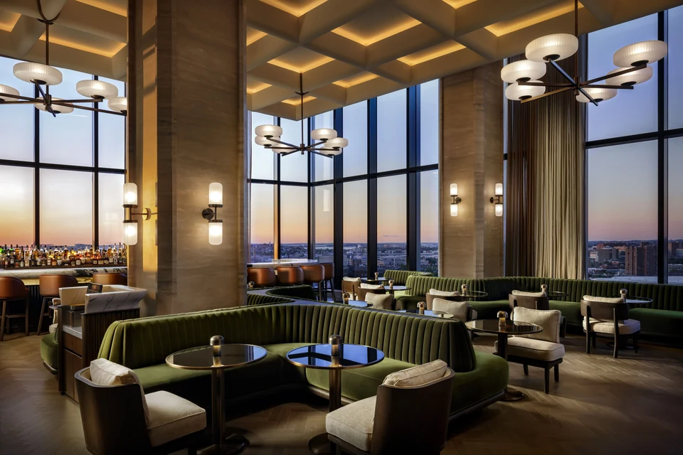 Raffles Boston lounge with floor-to-ceiling windows at dusk via Expedia