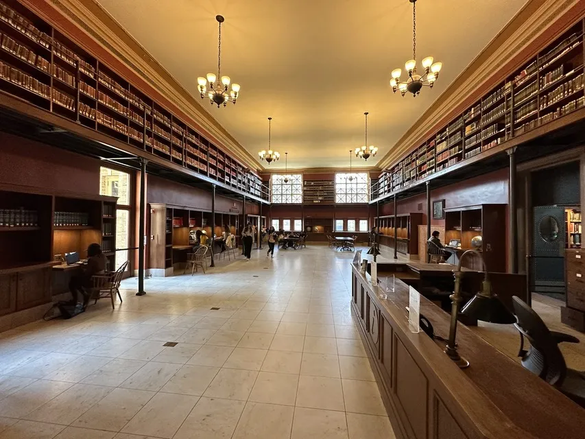 Long reading room with wood shelves and chandeliers at Boston Public Library