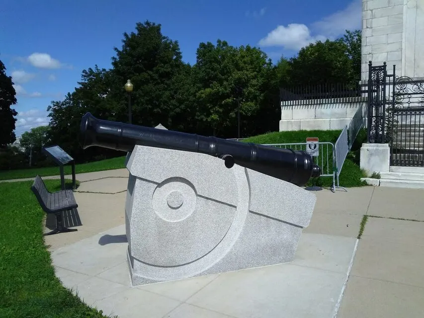 A cannon and the stone monument grounds at Dorchester Heights in South Boston on a sunny day