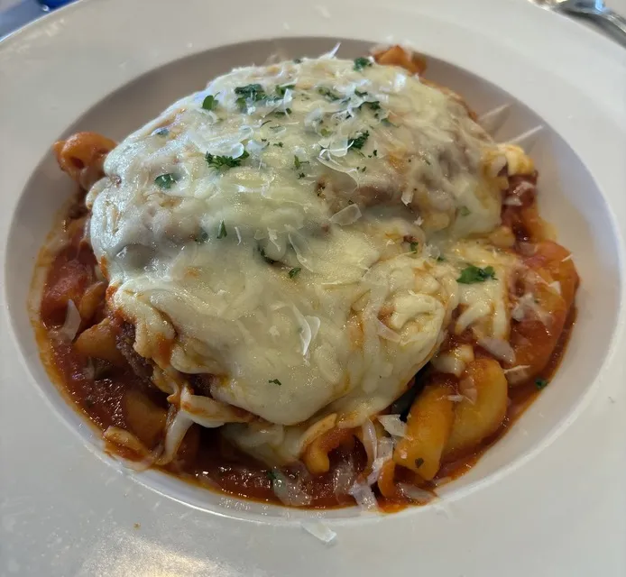 Baked pasta under melted cheese and tomato sauce in a white bowl